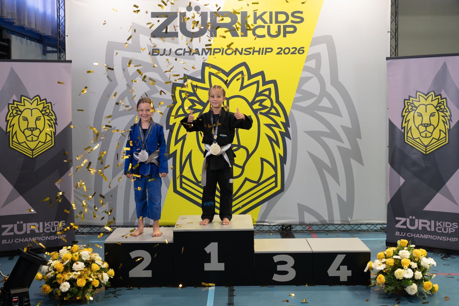 Aleyna zuoberst auf dem Podest mit der Gi-Goldmedaille am Züri Kids Cup BJJ Championship 2026, im Konfettiregen.